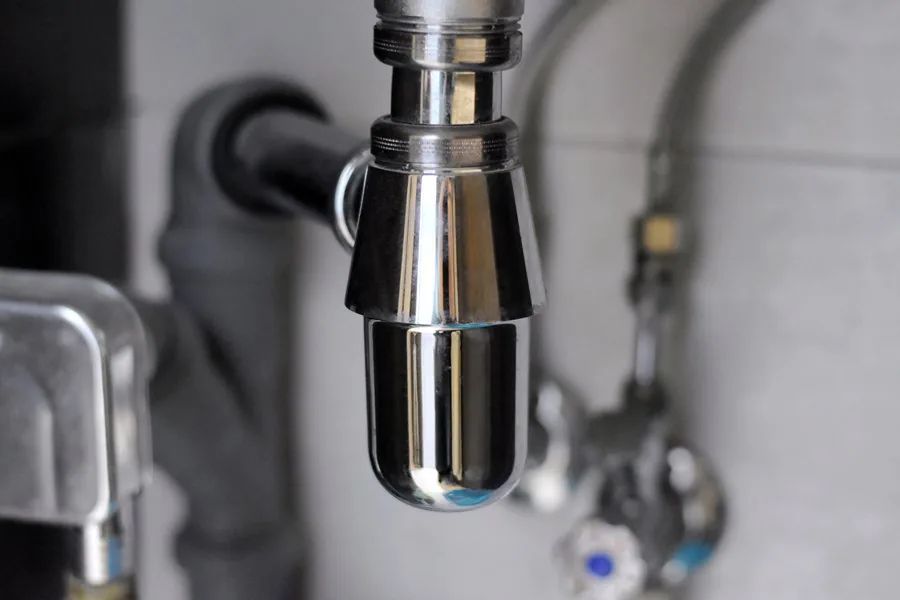 A close-up view of a faucet connected to a shiny metal pipe, showcasing intricate details and textures.