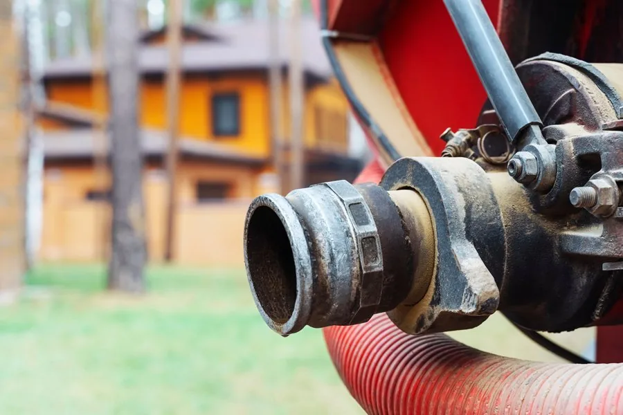 A close-up view of a hose connected to a fire hydrant, showcasing the details of the equipment and its fittings.