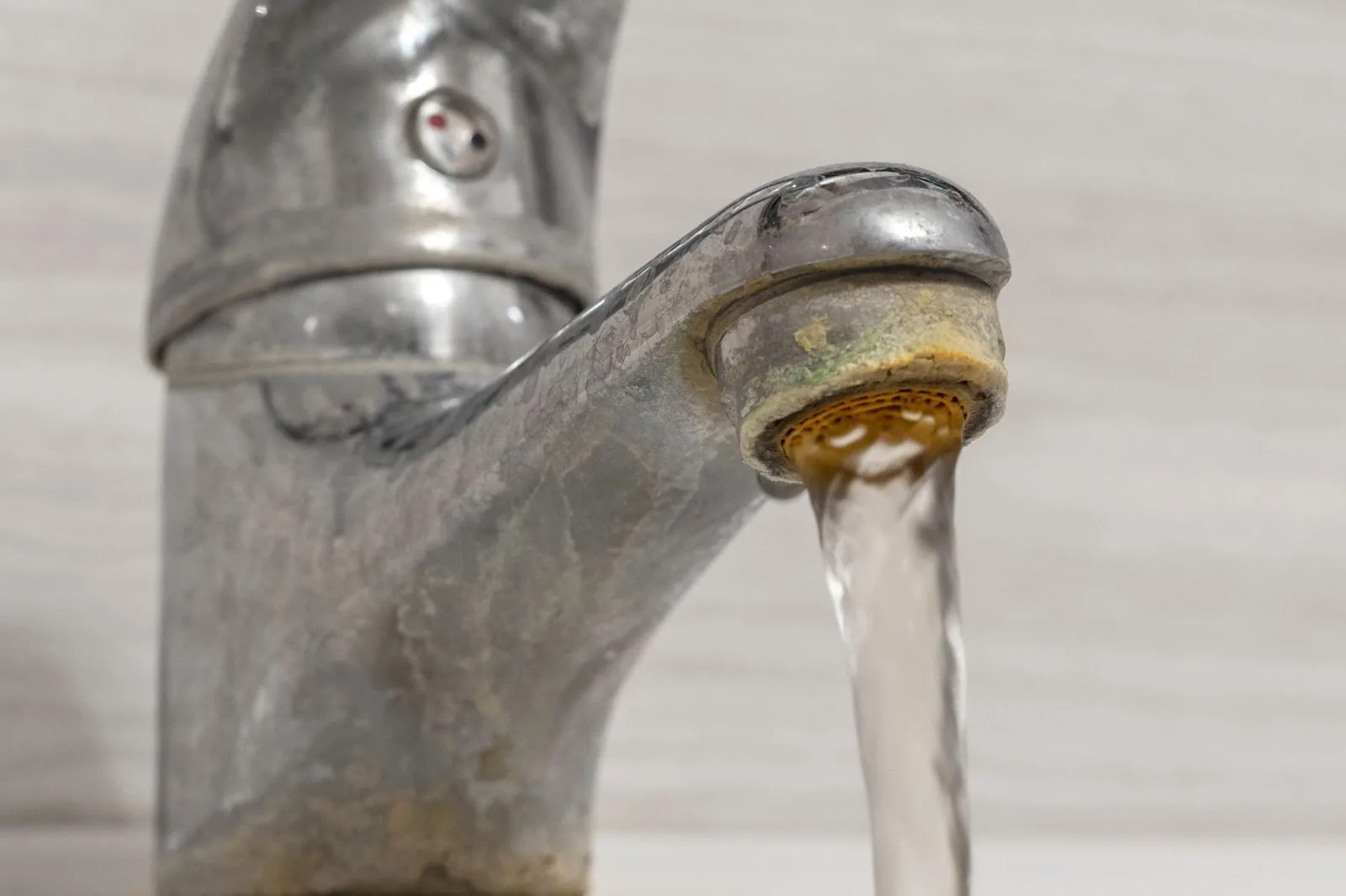 A faucet with water running from it, indicating plumbing problems and a leaky faucet due to hard water