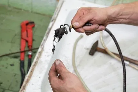 A man cleans a sink using a hose, demonstrating effective cleaning techniques and maintaining hygiene.

