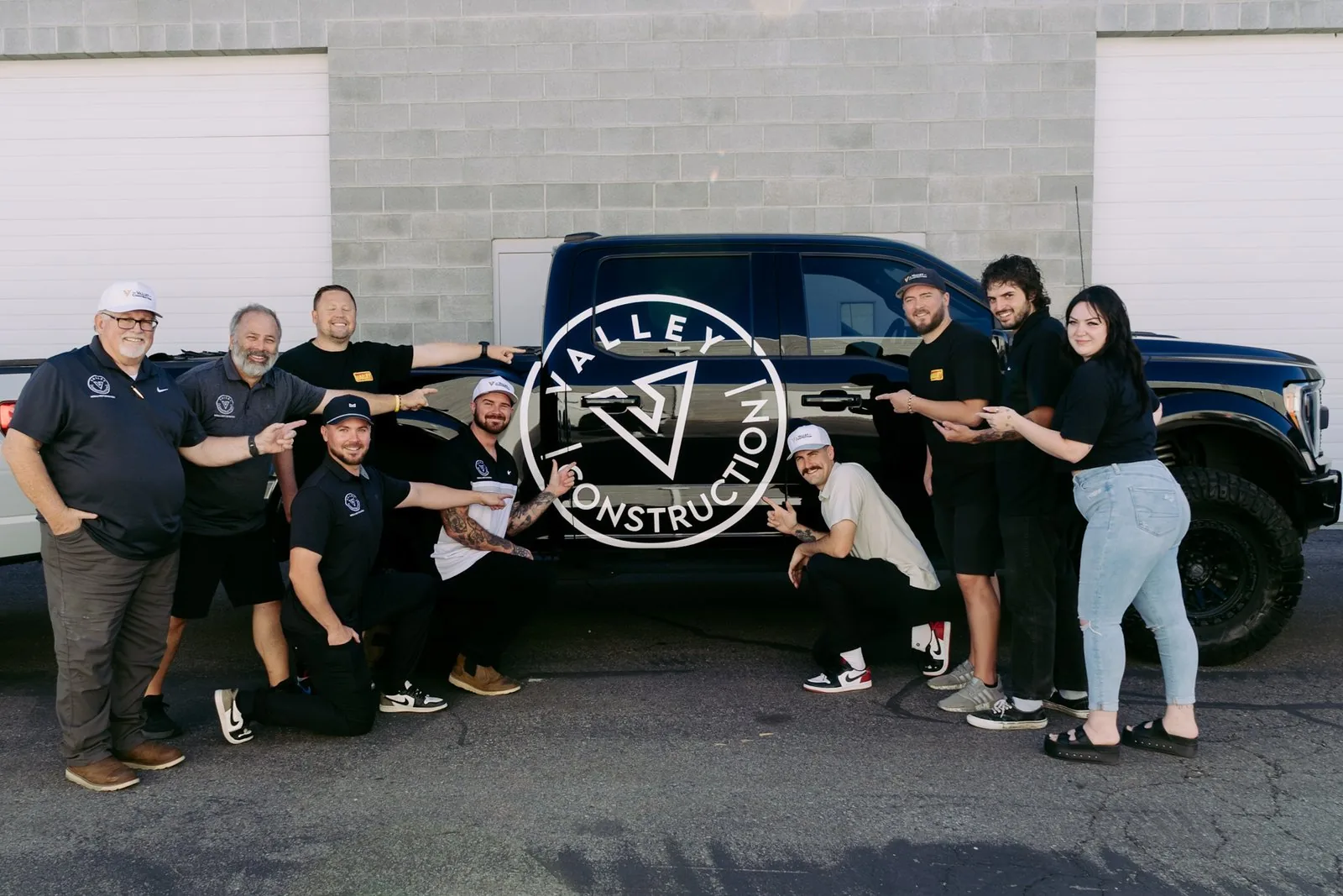 Valley Construction Team Pointing to Raptor Truck with Team Pointing to Valley Construction Logo Photo 1